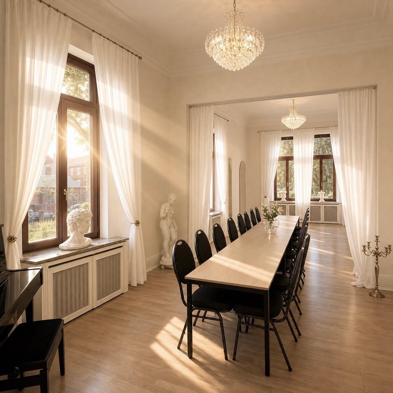 Lichtdurchfluteter LIVA-Eventraum mit langer Tafel, Kronleuchtern und hellen Vorhängen