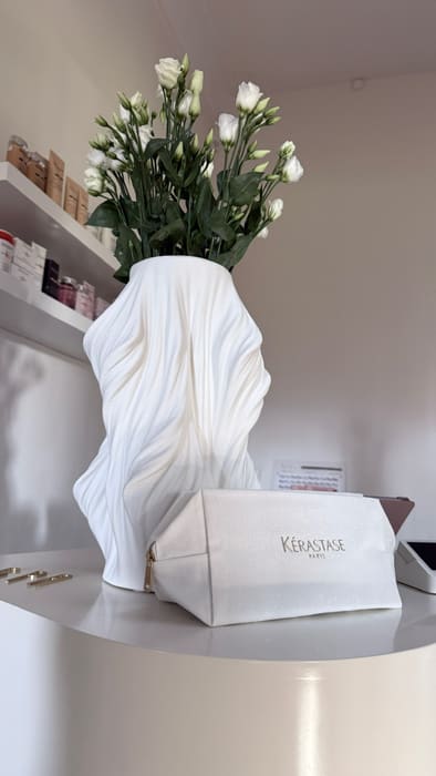 Weiße Vase mit Blumen und Pflegeprodukte